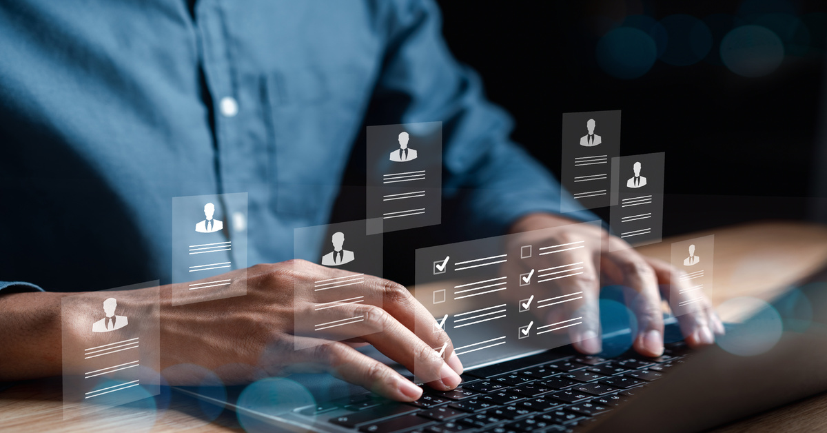 A man in a blue button down shirt types on a black keyboard while various icons and check marks surround him.