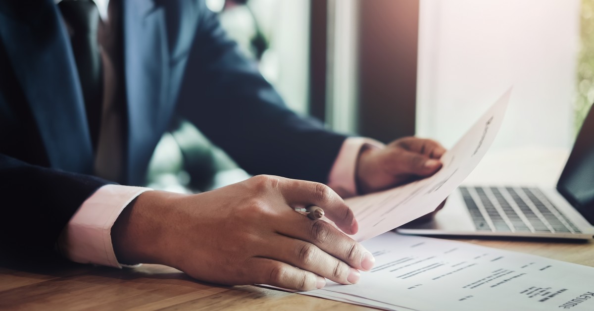 A business person wearing a suit looks at holographic icons of documents and selects the first one.