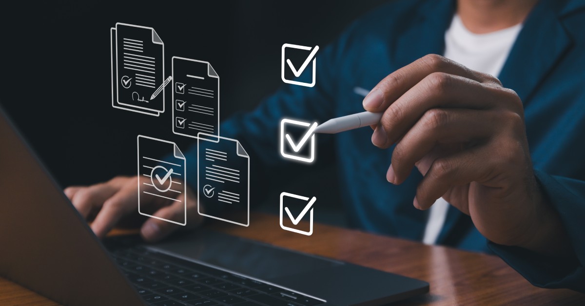 A person sits at a table with a laptop and interacts with holographic icons floating near the laptop.