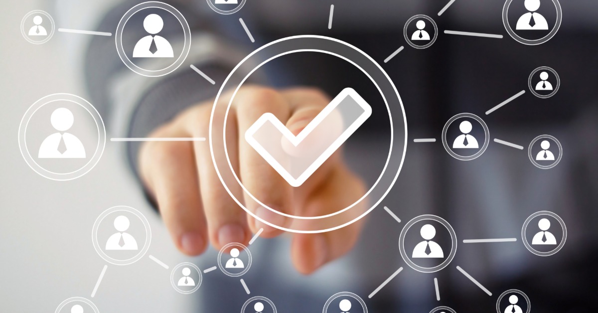 A businessman pushing a virtual icon of a checkmark that is connected to other small icons of people.